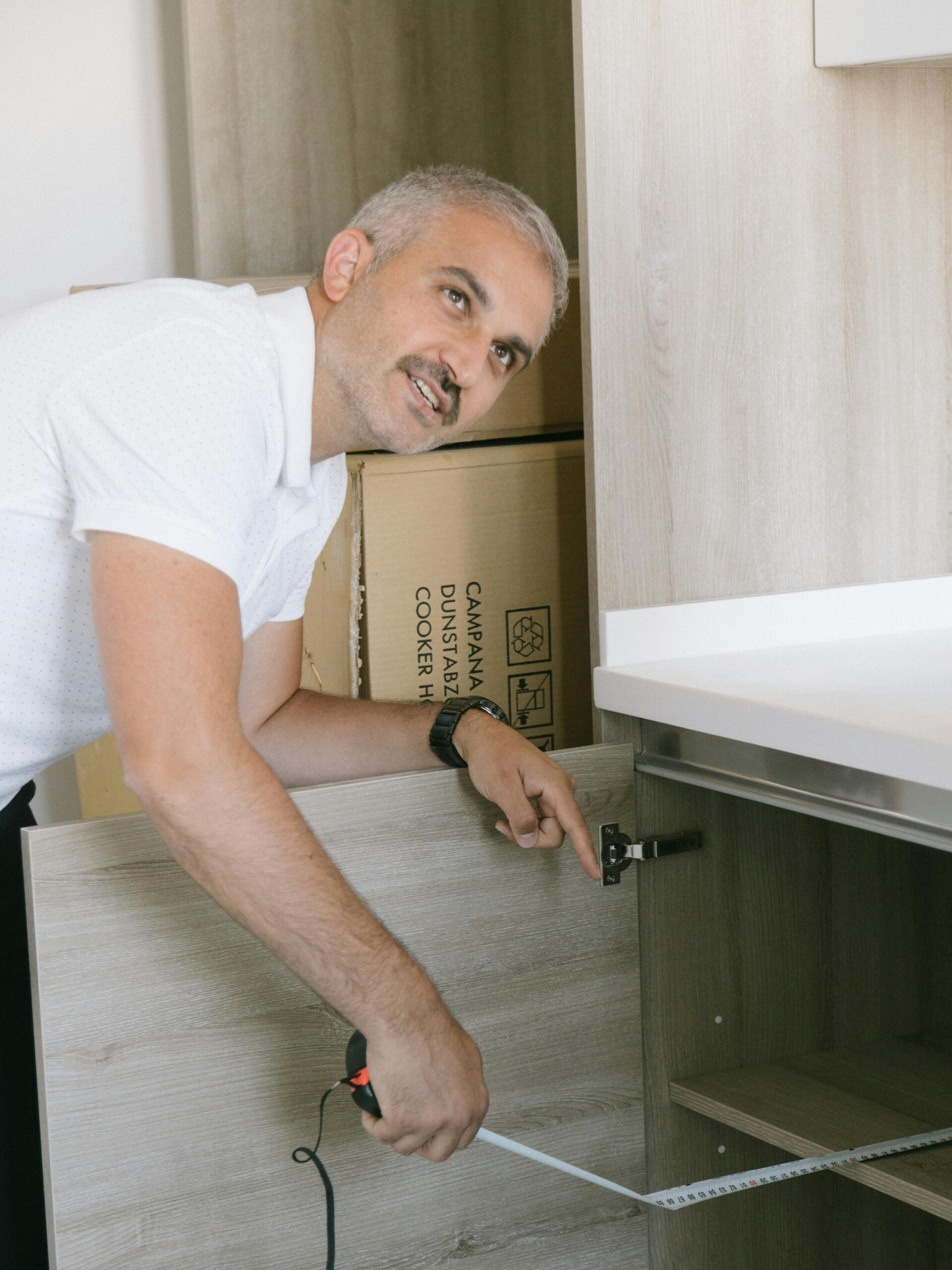 Handwerker misst Küchenschrank mit Lineal