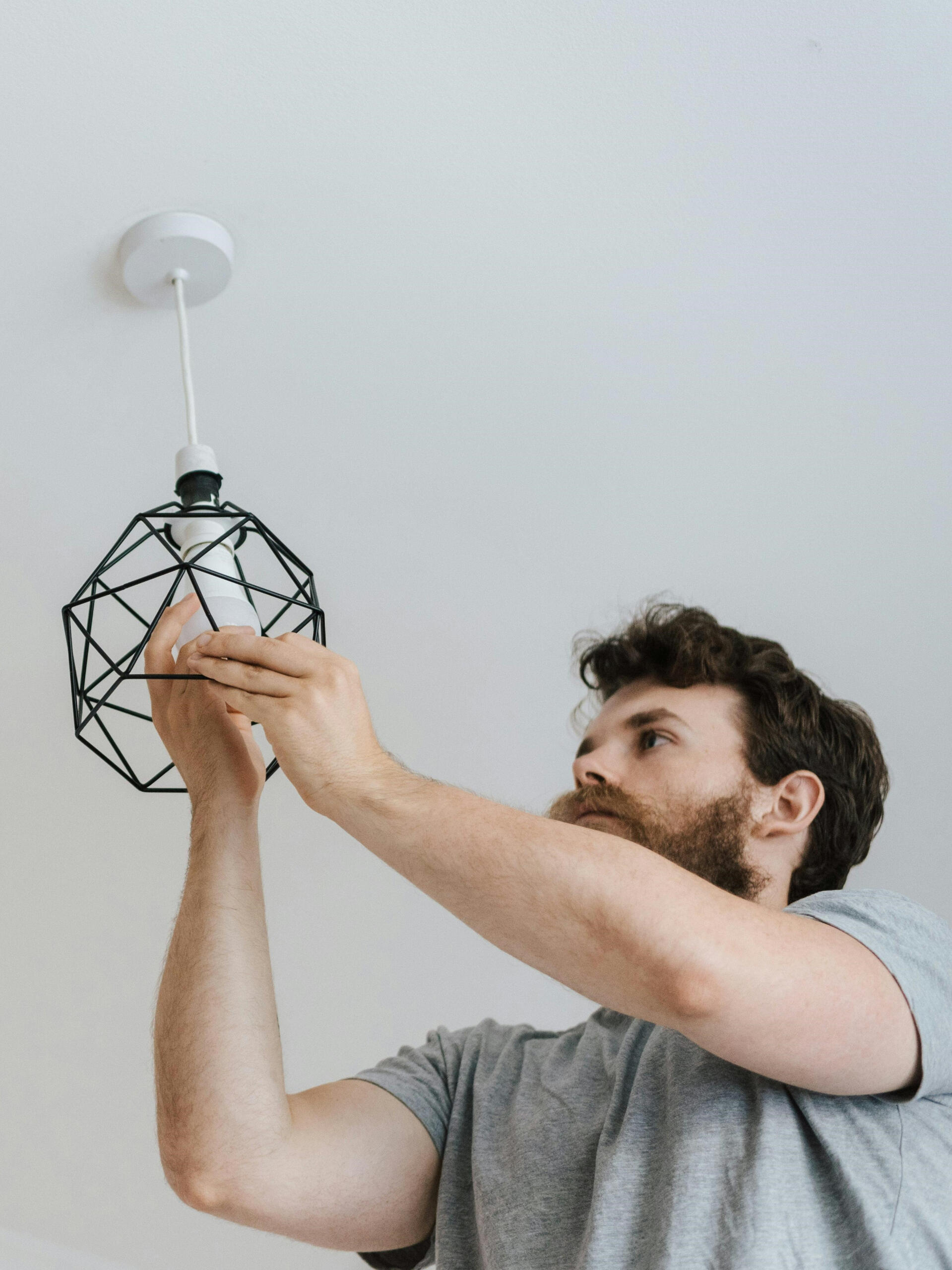 Handwerker wechselt Glühbirne in Schlafzimmer-Deckenlampe